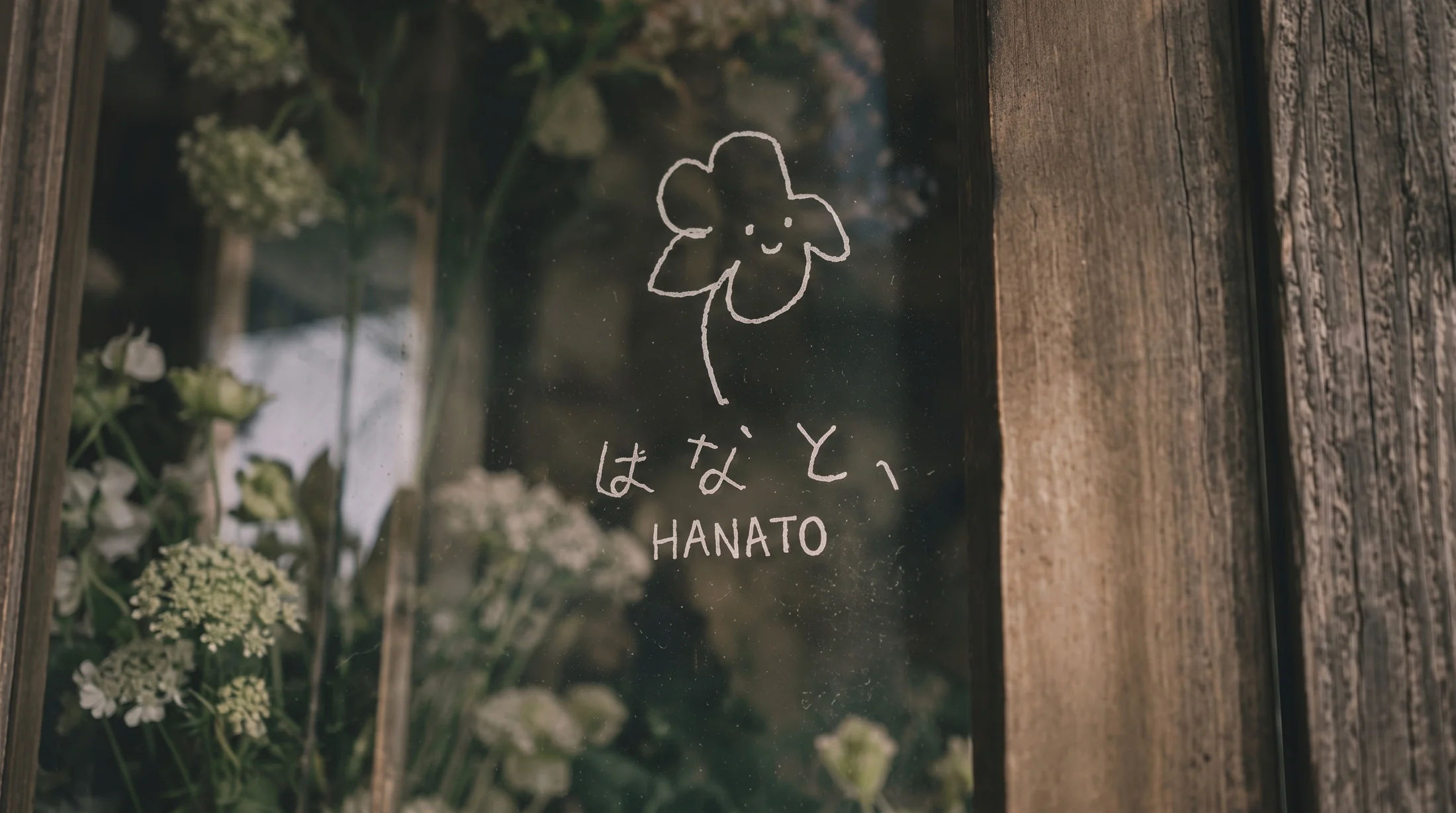 HANATO's hand-drawn flower logo on the glass of the flower shop